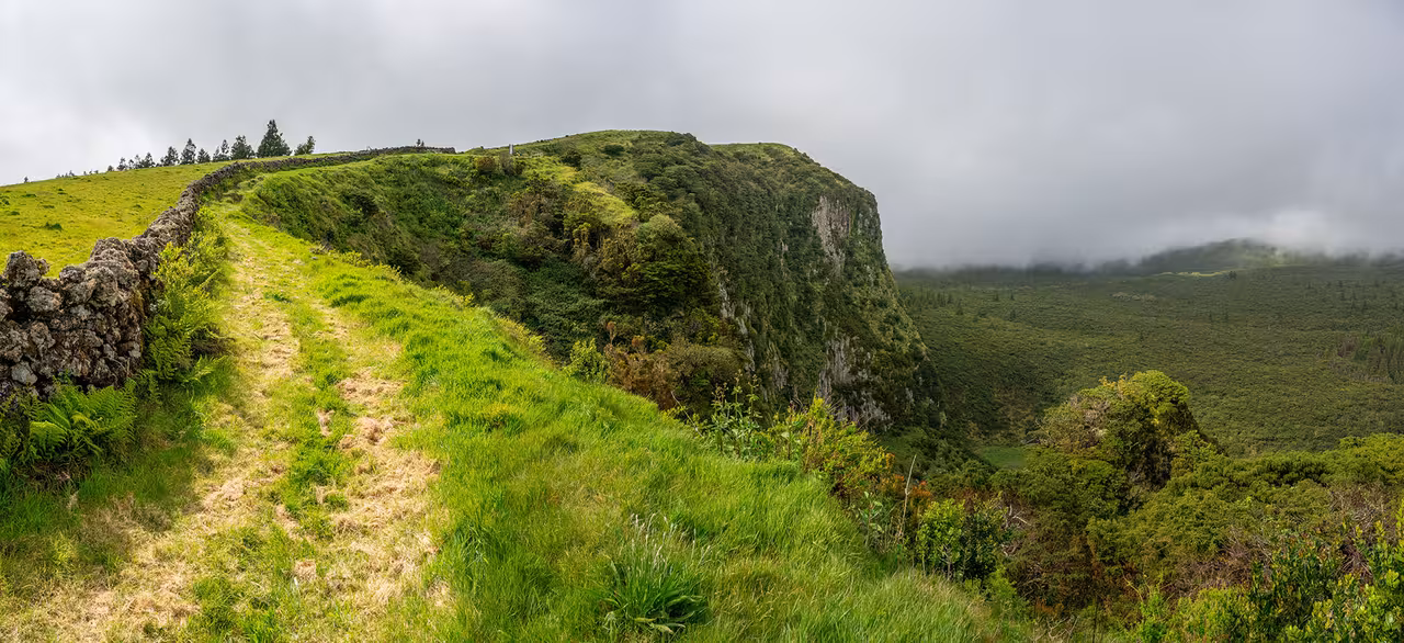 Clifftop trail beside stone wall on Chambre Rock full-day hiking tour, lush Azores views and lunch included