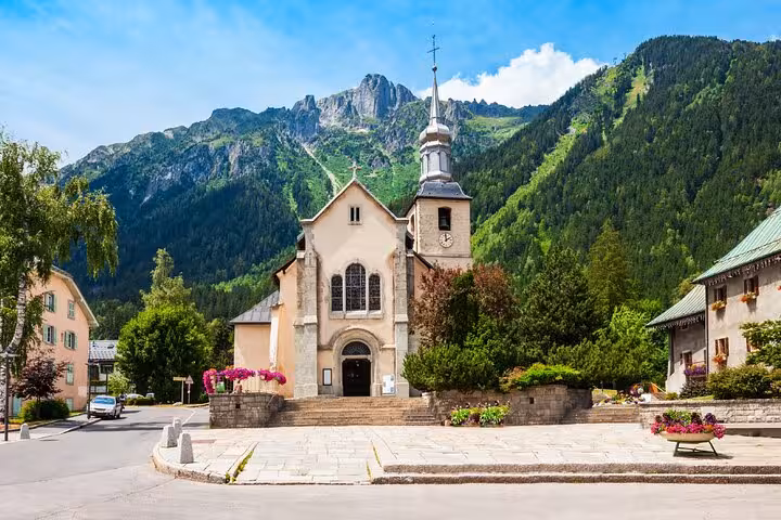 Historic church in Chamonix village square with dramatic Alpine mountain backdrop on sunny day