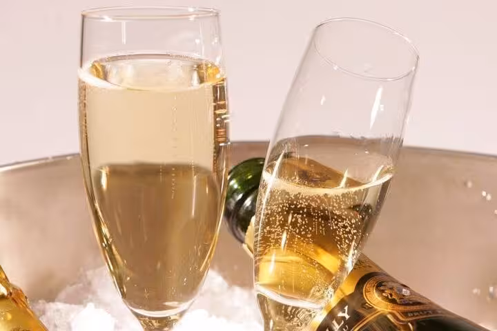 Two champagne flutes with sparkling wine next to a chilled bottle in an ice bucket