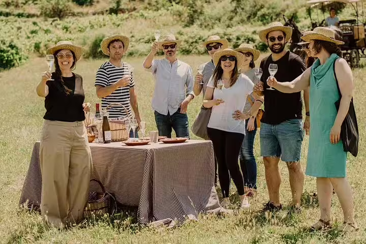 Group enjoying a champagne tasting at a vineyard in Reims with a picnic setup, part of a day trip from Paris with lunch.