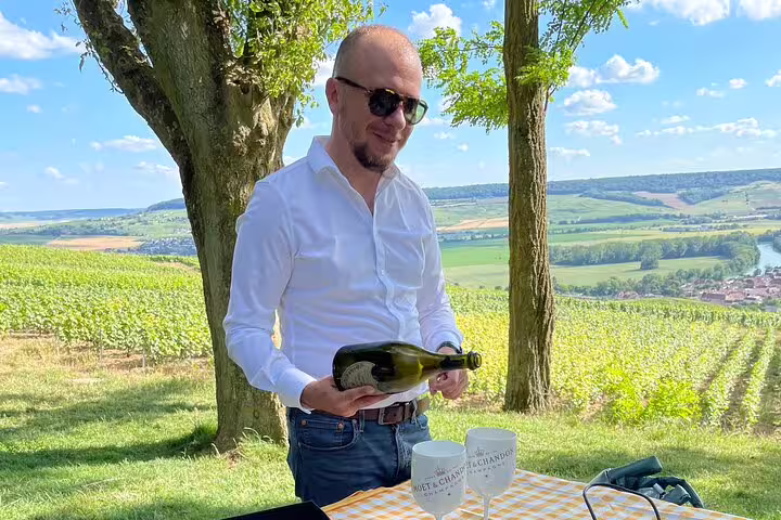 Champagne tasting in Reims vineyards, guide pouring bubbly during Champagne and Reims day trip from Paris