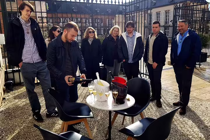 Champagne tasting stop on small-group day trip from Paris as guide pours bubbly at winery courtyard