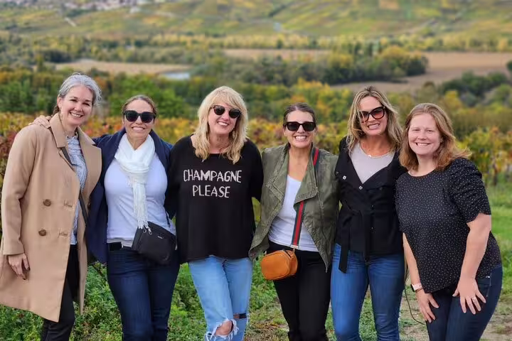 Small group in Champagne vineyards near Reims on a tasting day trip from Paris, scenic countryside backdrop