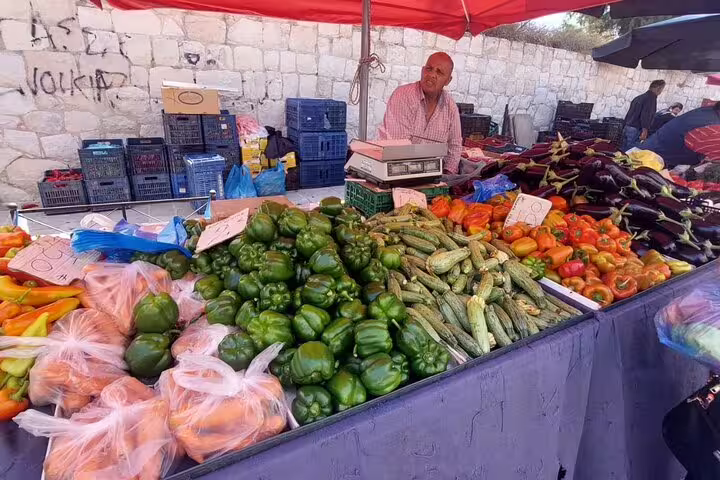 Vibrant farmers market stall in Chania Old Town displaying diverse fresh vegetables under a red canopy.