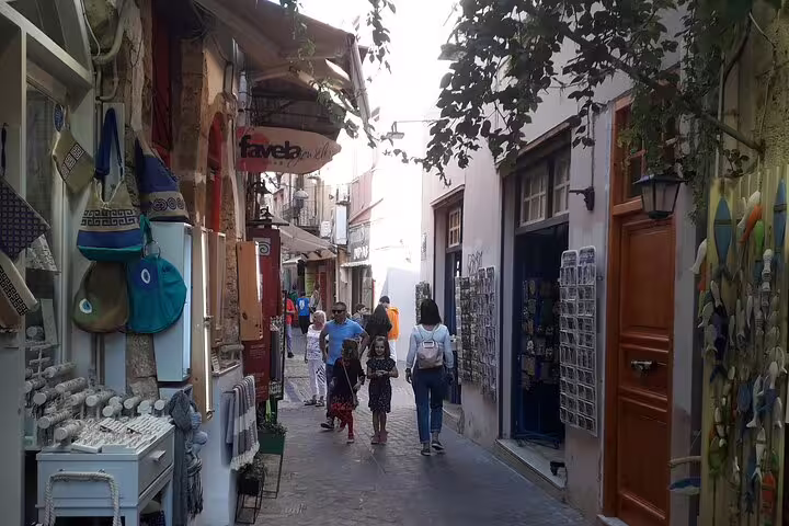 Chania Old Town's charming narrow alleyway lined with colorful shops and strolling tourists on a sunny day.