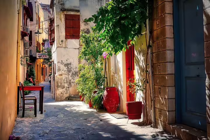 Charming narrow street in Chania Old Town, Crete, with colorful plants and traditional architecture on a sunny day.