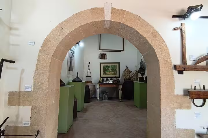 Historic archway leading to an exhibit of traditional olive oil mill artifacts in Chania Old Town, Crete.