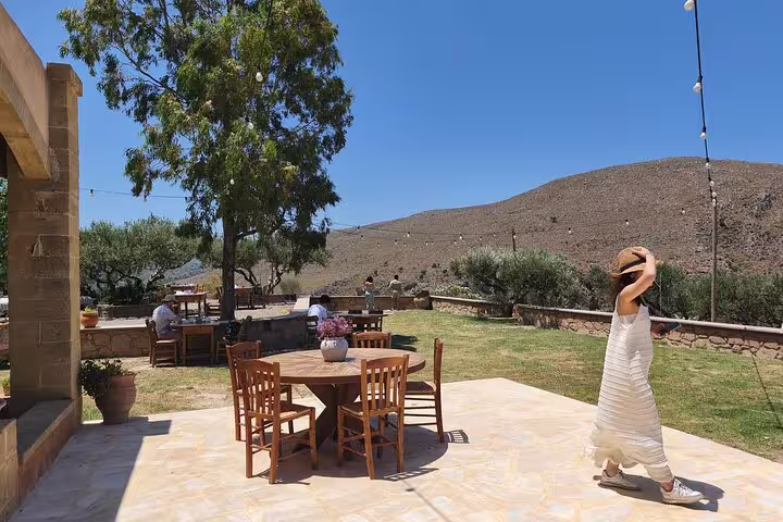 Relax in the serene outdoor seating area at Chania's olive oil mill, surrounded by lush landscapes and rolling hills.