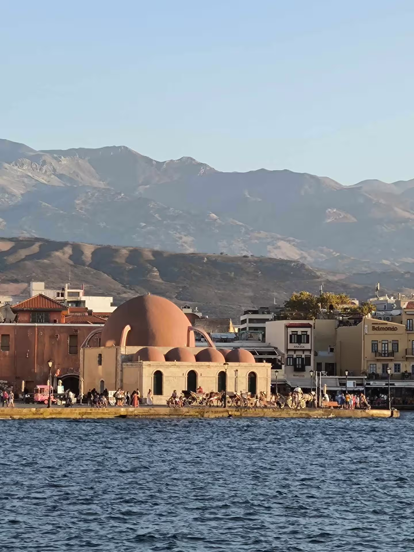 Scenic view of Chania's Venetian harbor with historic architecture and mountain backdrop, perfect for Aptera tour enthusiasts.