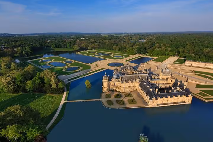 Aerial view of Château de Chantilly surrounded by moat and formal French gardens in Oise, France