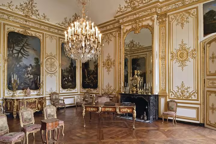 Ornate gilded salon with crystal chandelier, baroque paintings, and parquet floors at Chantilly Chateau