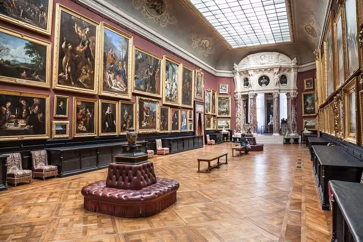 Grand gallery of Chantilly Chateau with floor-to-ceiling oil paintings, parquet floors, and tufted leather seating