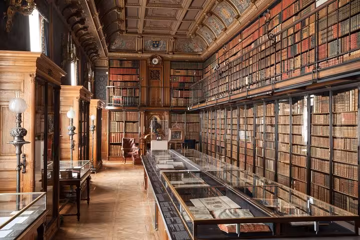 Grand historic library at Chantilly Chateau with floor-to-ceiling bookshelves and ornate painted ceiling
