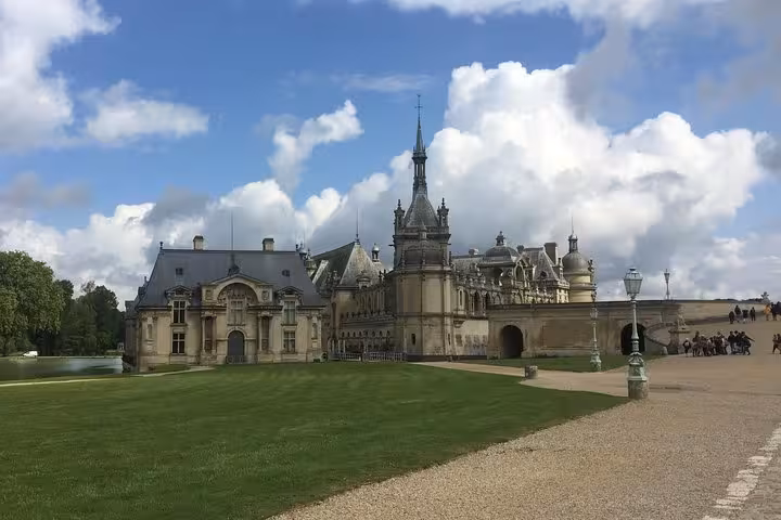 Château de Chantilly grand facade with manicured lawns and ornate towers under blue sky
