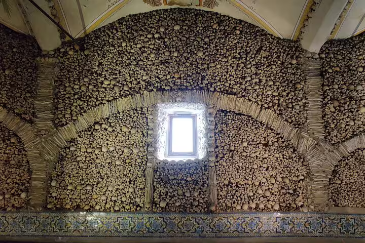 Interior view of the Chapel of Bones in Évora, showcasing walls adorned with human skulls and bones, a highlight of the day tour to Évora and Monsaraz.