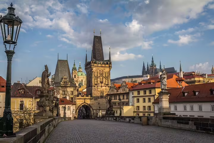 Charles Bridge with gothic tower and Prague Castle skyline on a sunny day