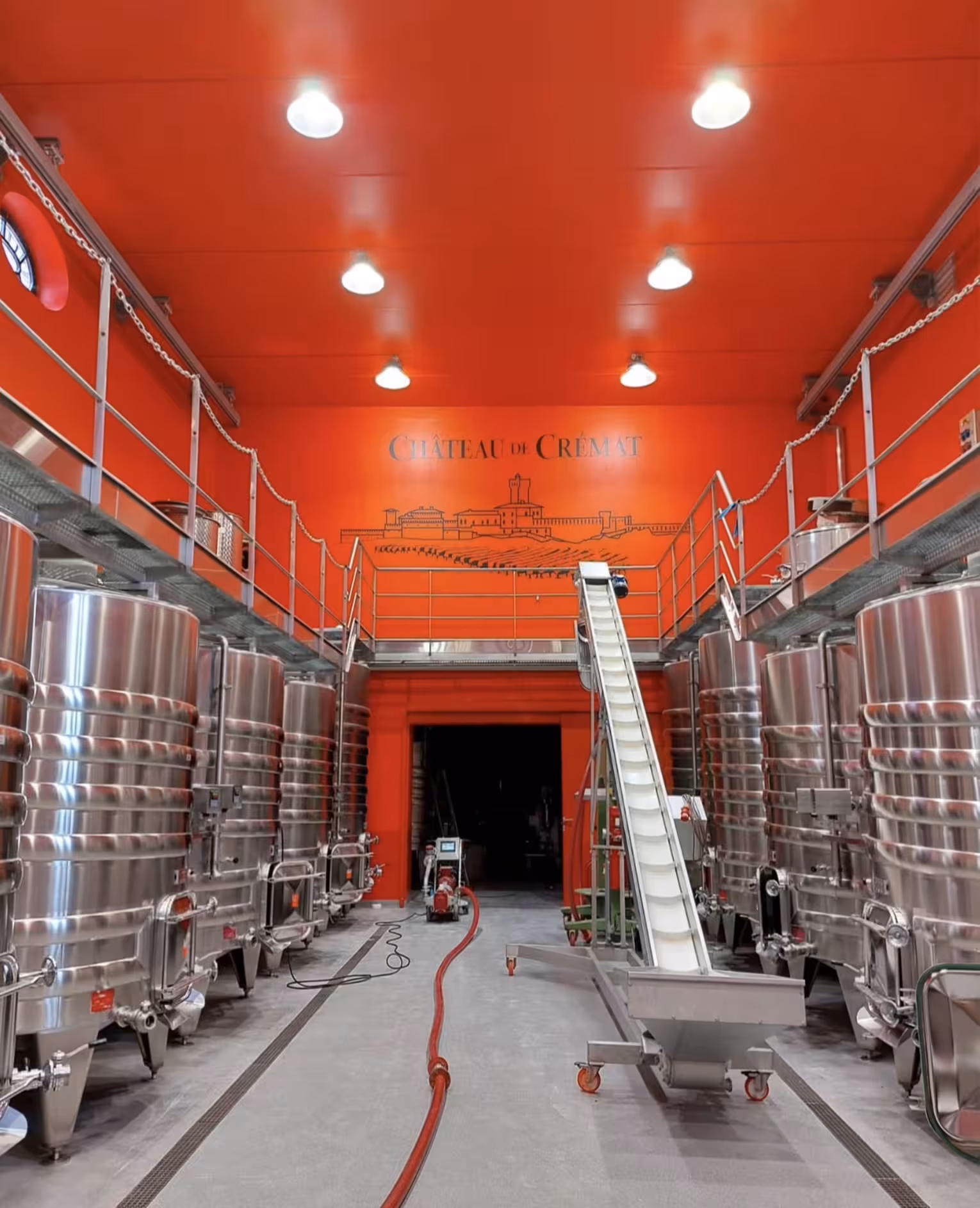 Château de Crémat winery fermentation hall with stainless steel tanks and red walls, Nice