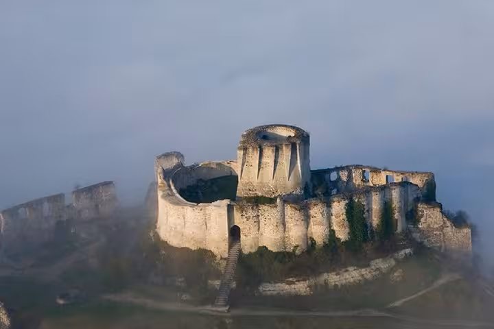 Aerial view of medieval Château Gaillard ruins on a hilltop shrouded in morning mist, Normandy
