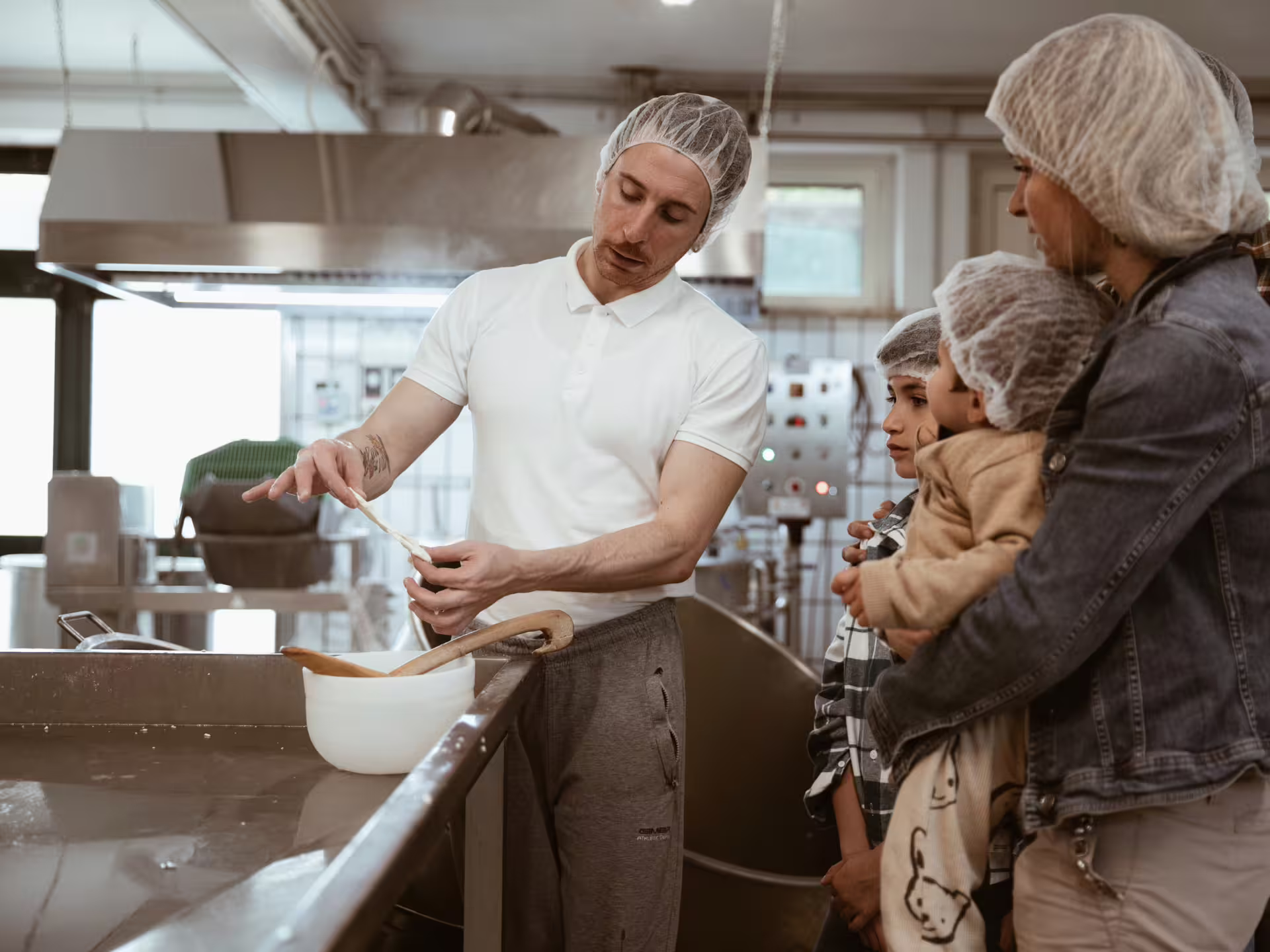 Cheese maker demonstrating cheese stretching to a family during a factory visit in Isernia countryside.