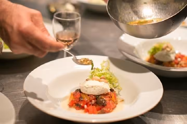 Chef plates a refined Provençal dish during an Avignon cooking workshop, paired with local wine tasting