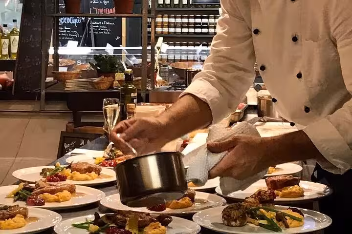 Chef plating Provençal dishes during Avignon cooking workshop, finishing sauces on gourmet plates