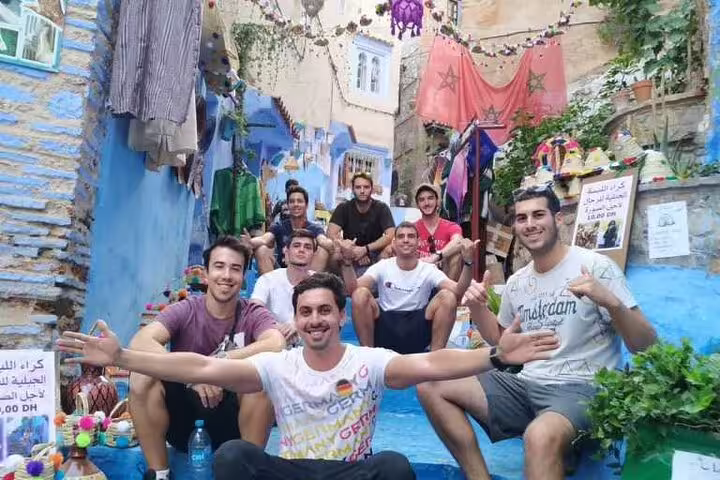 Friends posing on blue-painted stairs in Chefchaouen medina on a 2-day trip from Casablanca, Morocco