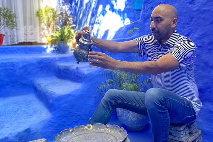 Traveler pours Moroccan mint tea in Chefchaouen’s blue medina courtyard on 2-day Casablanca to Chefchaouen tour