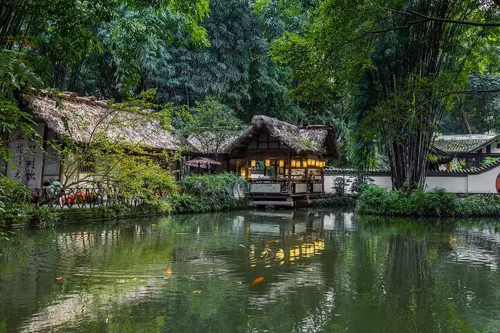 Serene bamboo grove surrounding a traditional thatched cottage by a pond in Chengdu, part of a private city tour experience.
