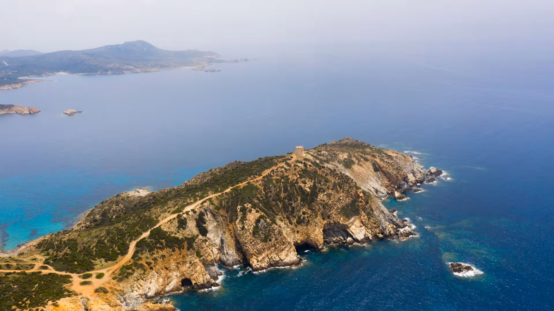 Aerial view of Chia's rugged coastline with crystal-clear waters, highlighting the scenic route of the 4-hour dinghy tour.