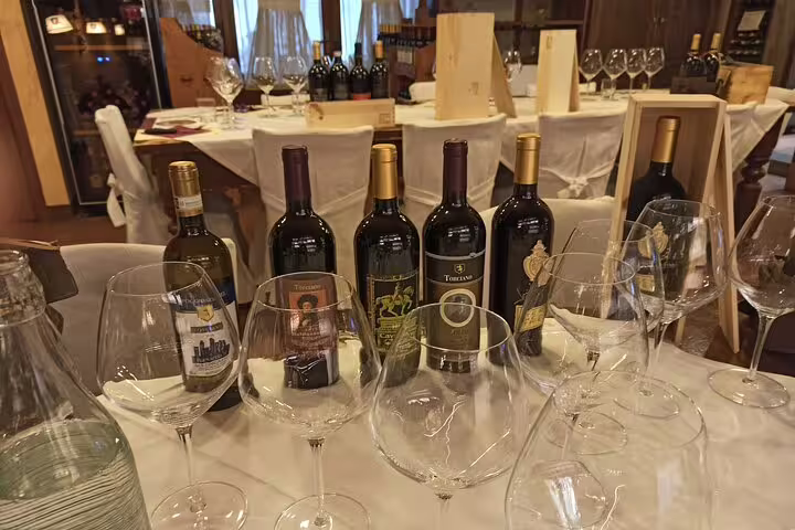 Guided Chianti Classico and Super Tuscan wine tasting in Tuscan cellar, with bottles and crystal glasses set for tour guests