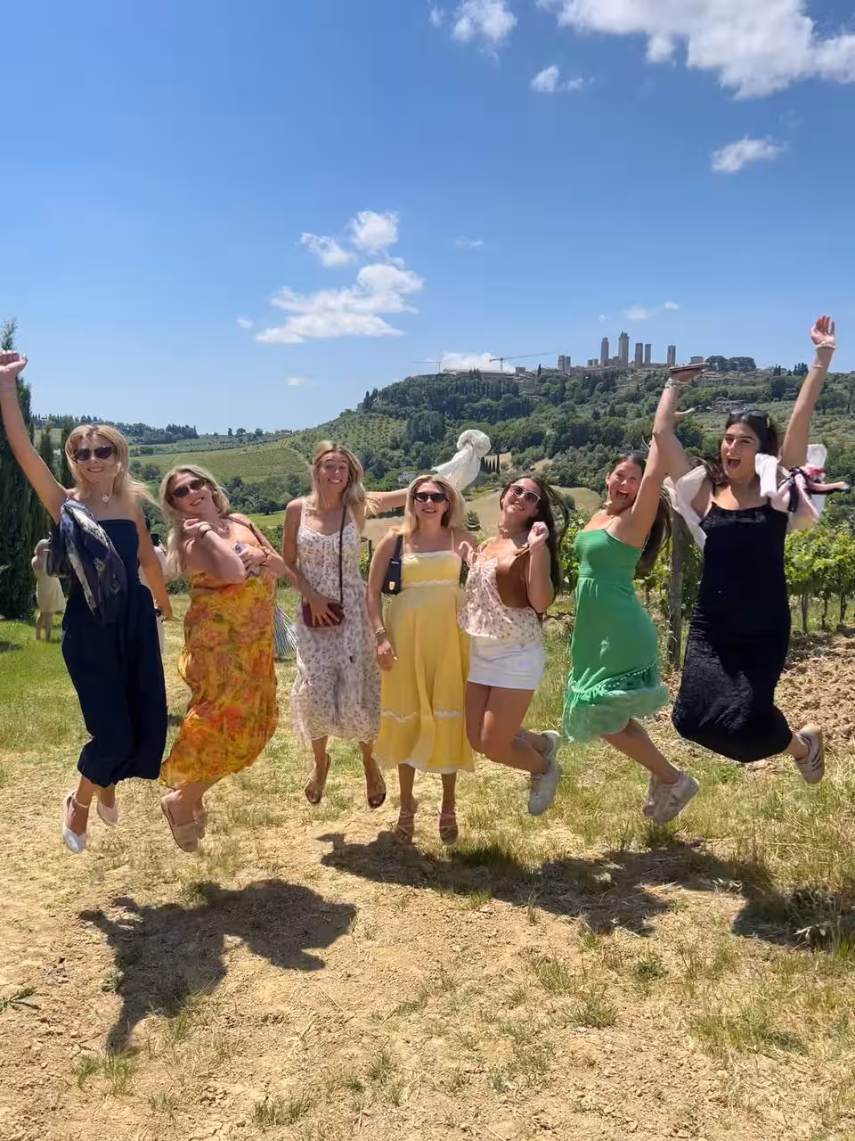 Group of friends joyfully jumping in a vineyard in Chianti, capturing the essence of a lively winery tour.