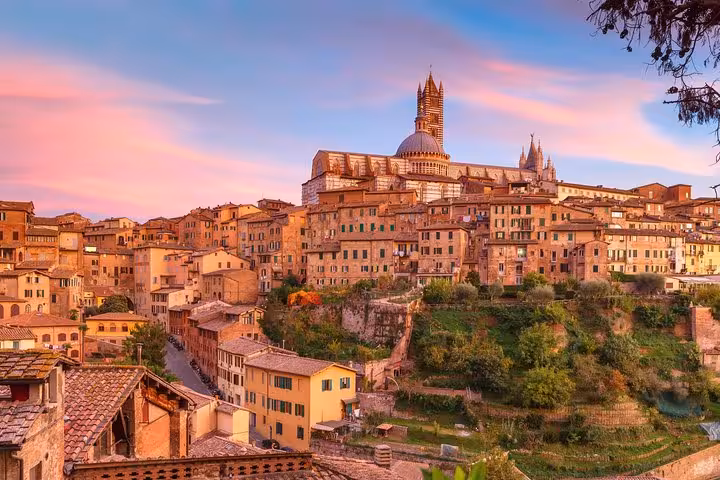 Breathtaking sunset view of Siena's historic skyline, featuring iconic architecture on the Florence wine tour.