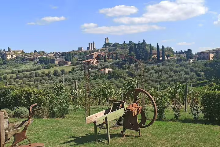 Rustic vineyard with old farm equipment overlooking rolling Chianti hills and San Gimignano skyline on Tuscany wine experience