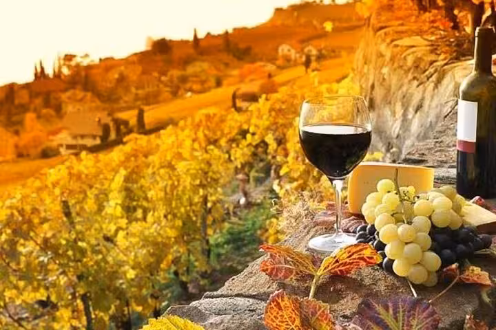 Scenic Chianti vineyard with wine glass, cheese, and grapes at sunset, ideal for private dinner and tasting tours.