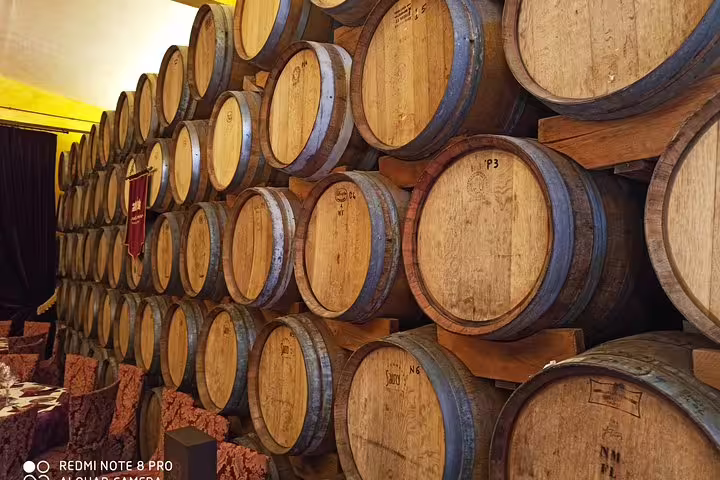 Aged oak wine barrels stacked in a rustic Chianti cellar visited on the private Pisa and Tuscan wine tasting day tour