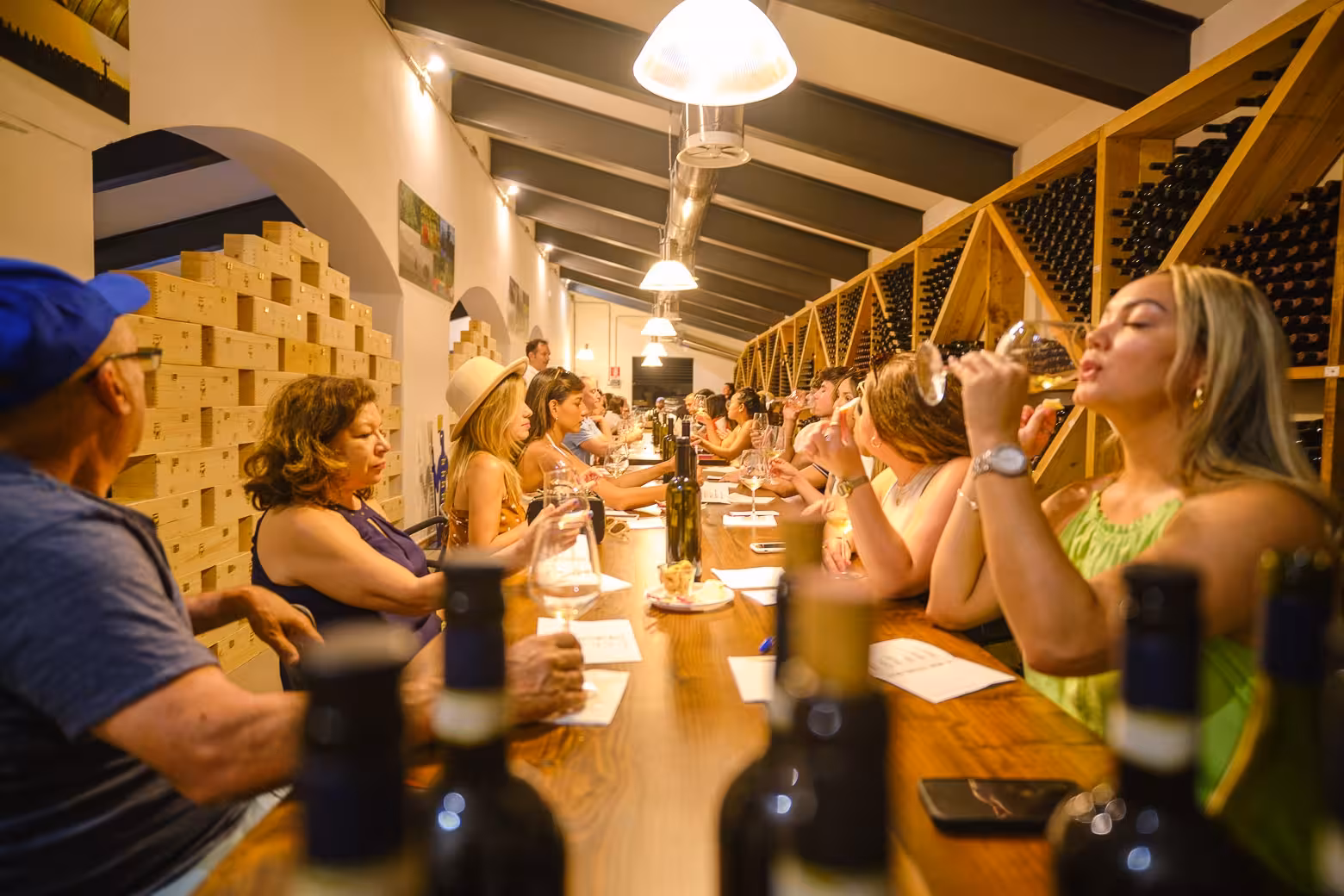 Visitors savoring wine during a tasting session in a Chianti winery, surrounded by bottles and wooden decor.