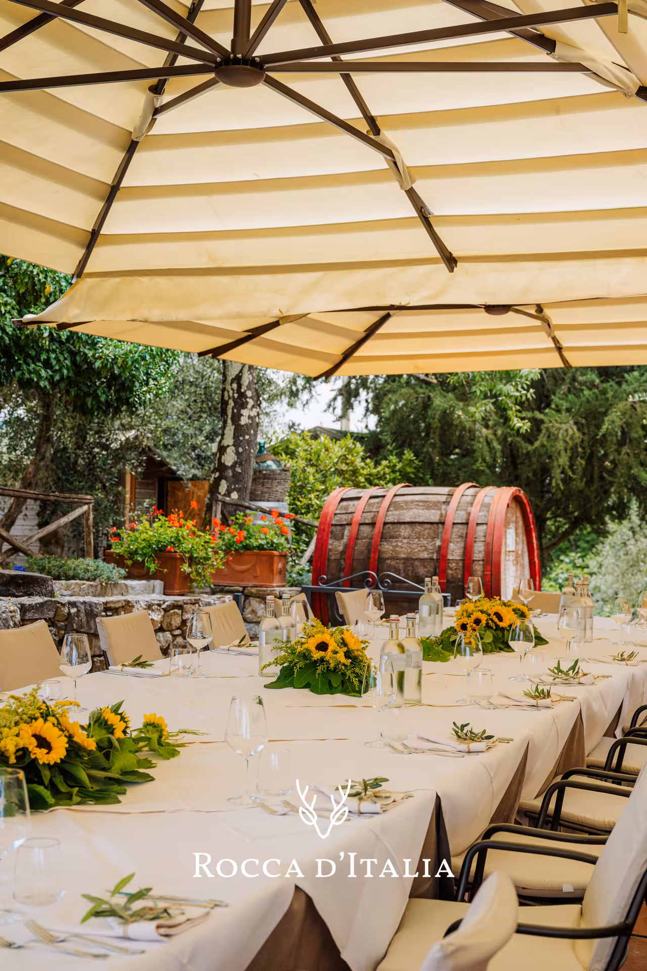 Elegant outdoor dining table with sunflowers and wine glasses at a Chianti winery with large wooden barrel
