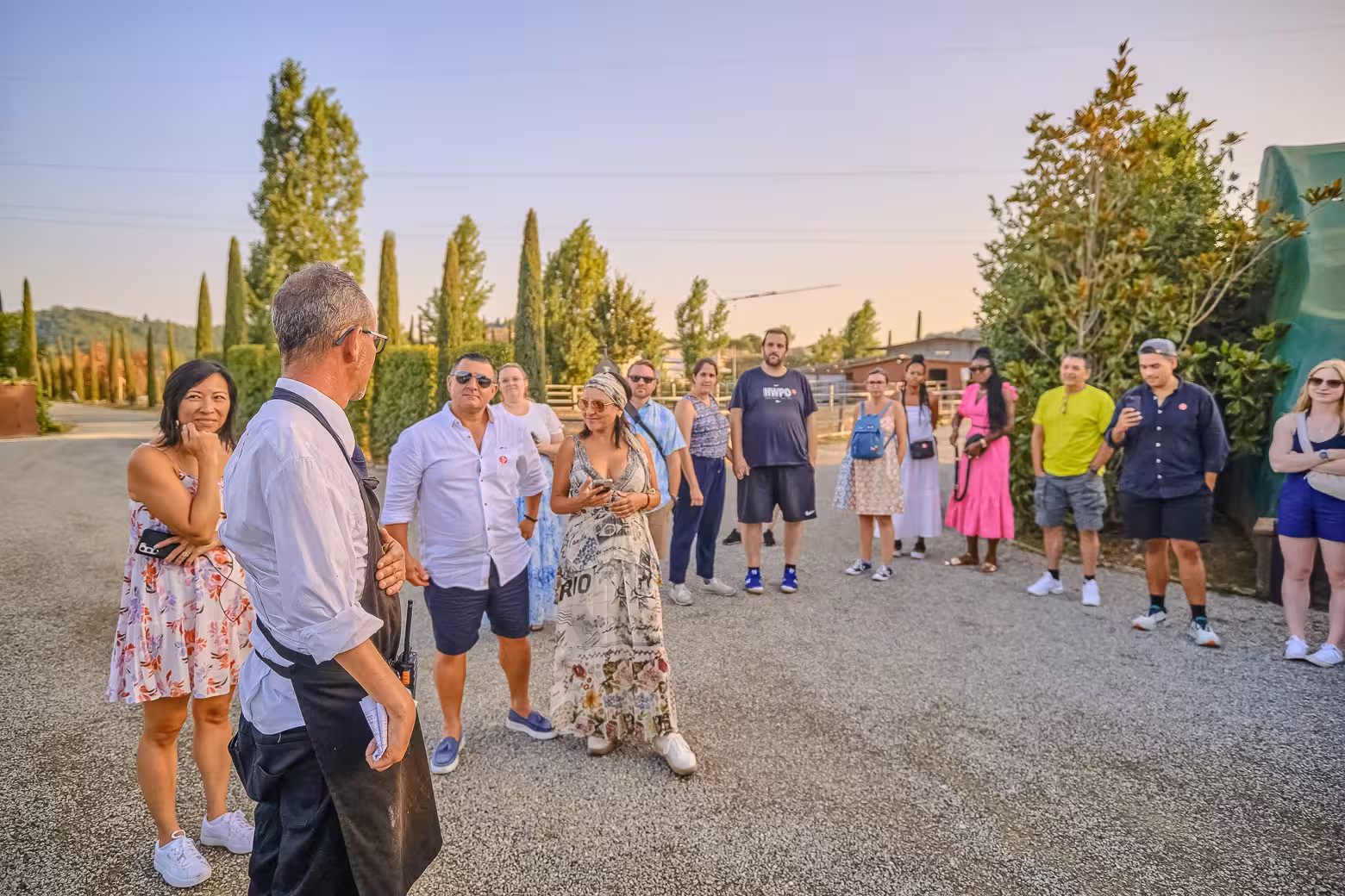 Tour group listening to a guide at a picturesque Chianti winery during a small-group tasting and dinner tour.