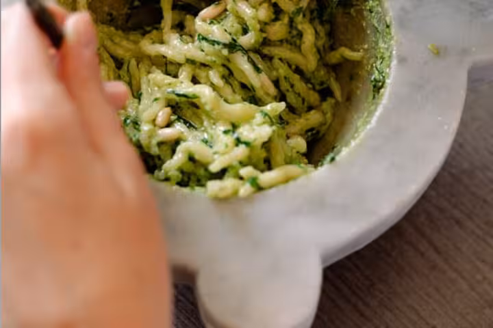 Pasta being prepared with freshly made pesto in a marble mortar, highlighting Chiavari's culinary tradition.