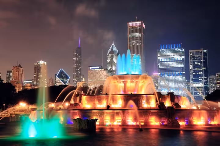 Buckingham Fountain illuminated at night with colorful lights and Chicago skyline in background