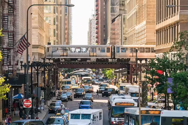 Busy Chicago street with elevated L train passing over traffic between tall downtown buildings
