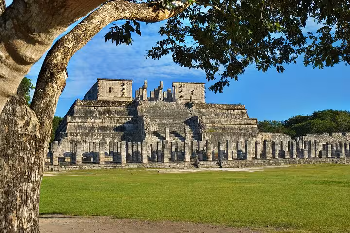 Ancient Mayan Temple of Warriors at Chichen Itza framed by trees under a bright blue sky in Yucatan Mexico