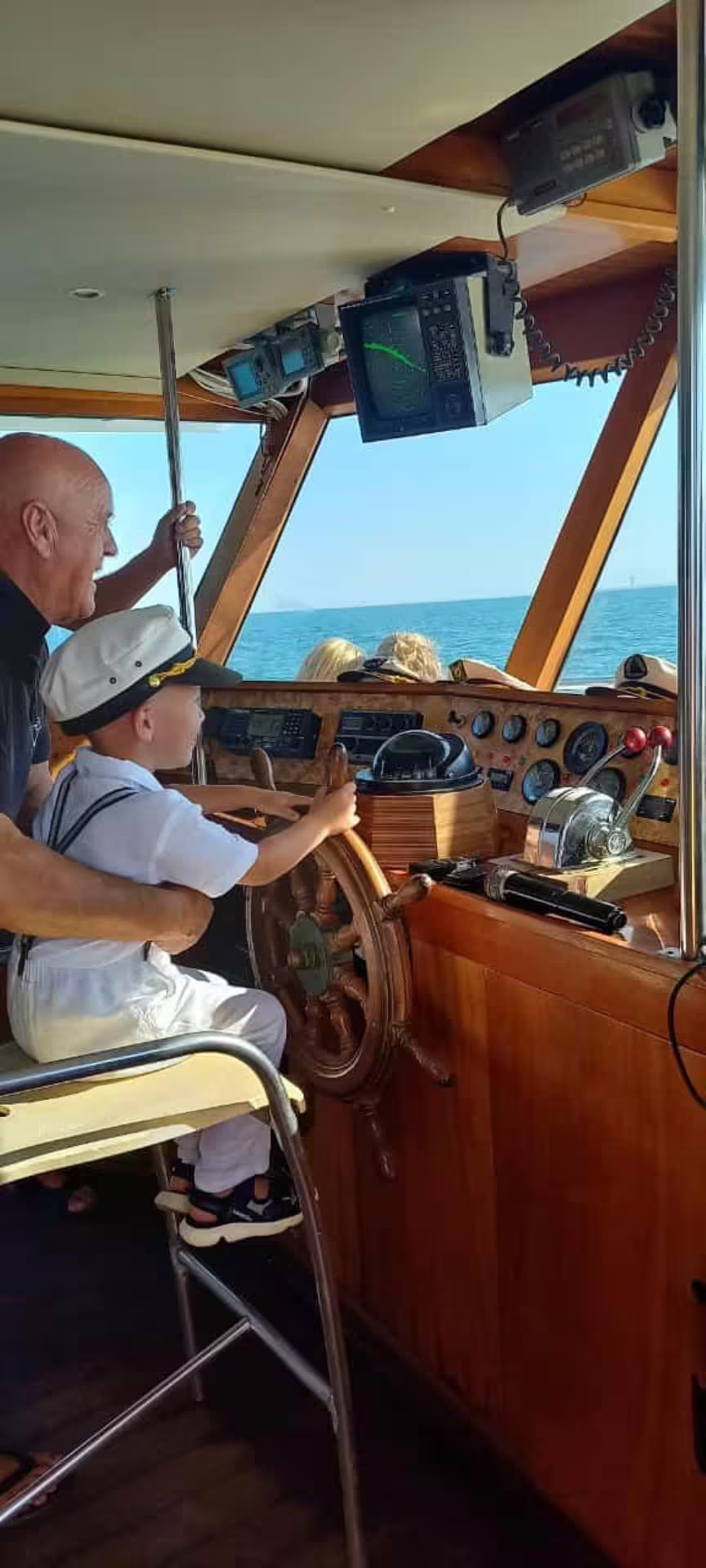 Child at the helm in the boat cockpit on a Riviera Romagnola half-day boat tour along the Adriatic coast