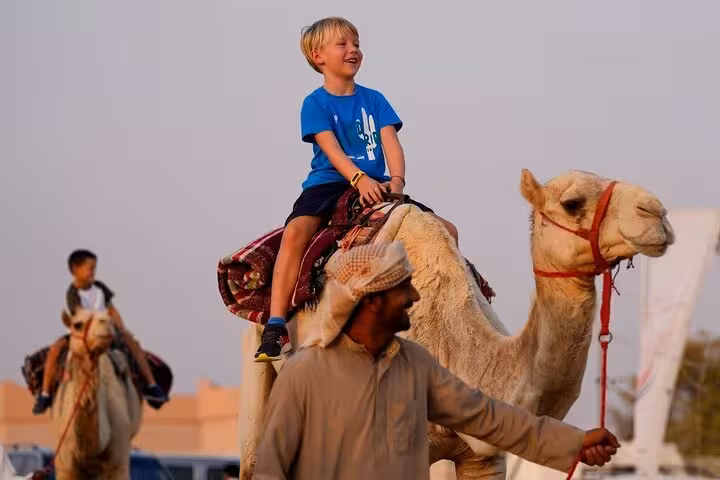 Child enjoying a camel ride in Hurghada with local guide, part of a one-hour desert adventure with transfers
