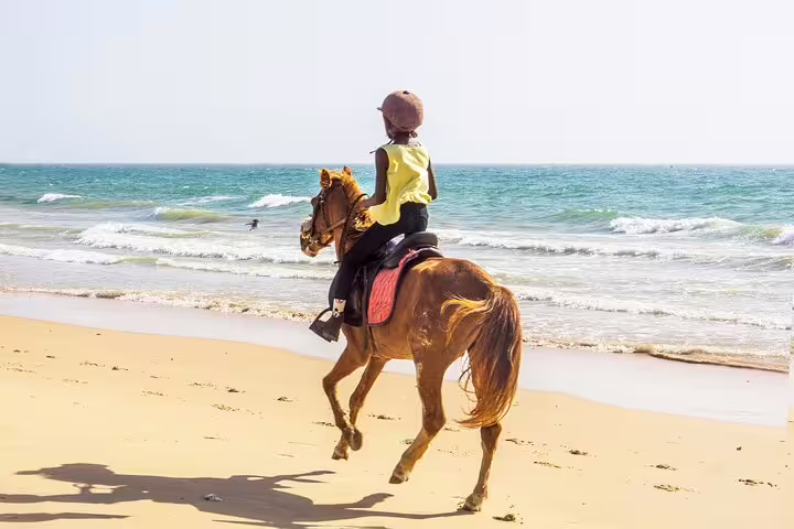 Child riding a horse along the scenic beach of Sal Island, ideal for a relaxing and adventurous holiday experience.
