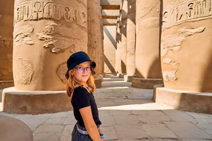 Child exploring Karnak Temple columns in Luxor on Sharm El Sheikh to Luxor flight tour, ancient Egypt