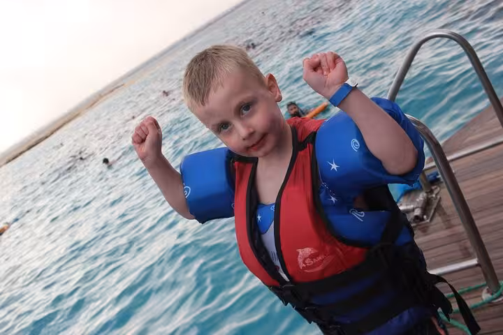 Child in life jacket on boat ladder during Hula Hula Island Hurghada sea trip with snorkeling and lunch
