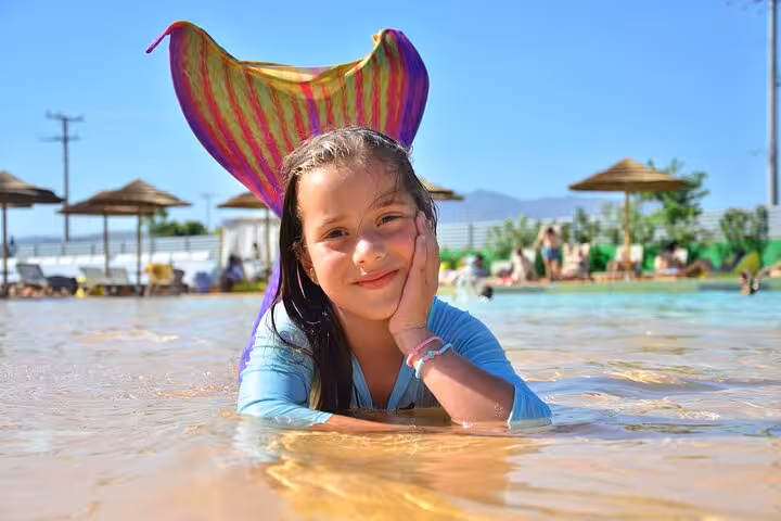 Smiling child with colorful mermaid tail in Hersonissos pool during a private photoshoot experience.