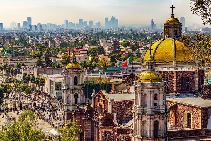 Golden domed churches of Chimalistac with Mexico City skyline and crowded plaza below