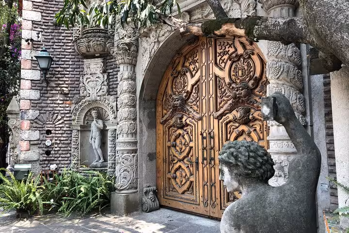 Ornate carved wooden doors with stone arch and classical statues at historic Chimalistac Mexico City entrance
